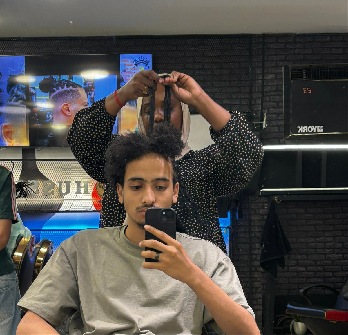Barber styling a customer's hair in a salon setting.